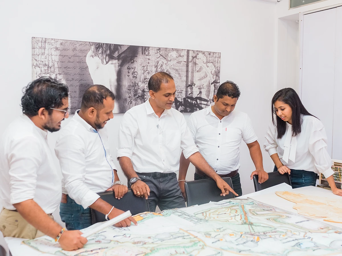 The team gathered around a site plan on the studio table