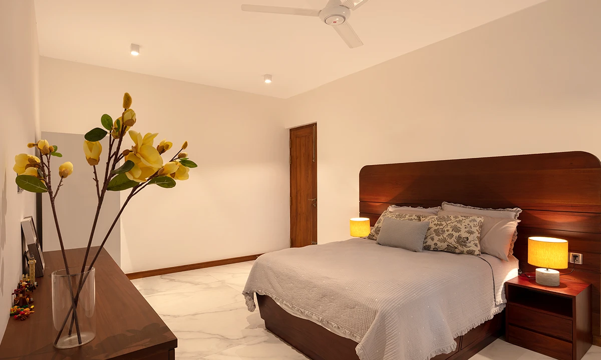 Bedroom with a curved timber headboard and yellow bedside lamps