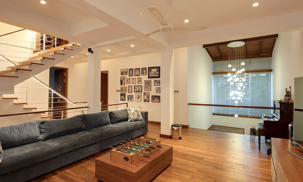 Family room with a long grey sofa, a timber floor and a stair with steel rails