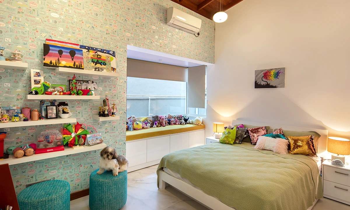 Child’s bedroom with patterned wallpaper, toy shelves and a window seat