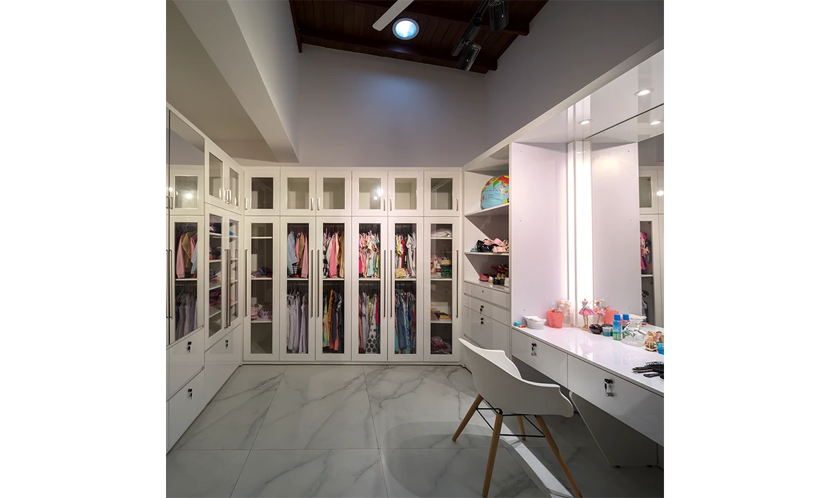 Walk-in wardrobe with white glass-fronted cabinets and a dressing table