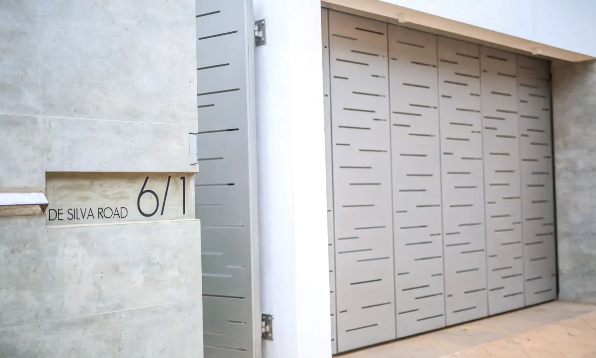 Perforated grey metal gate in the concrete boundary wall