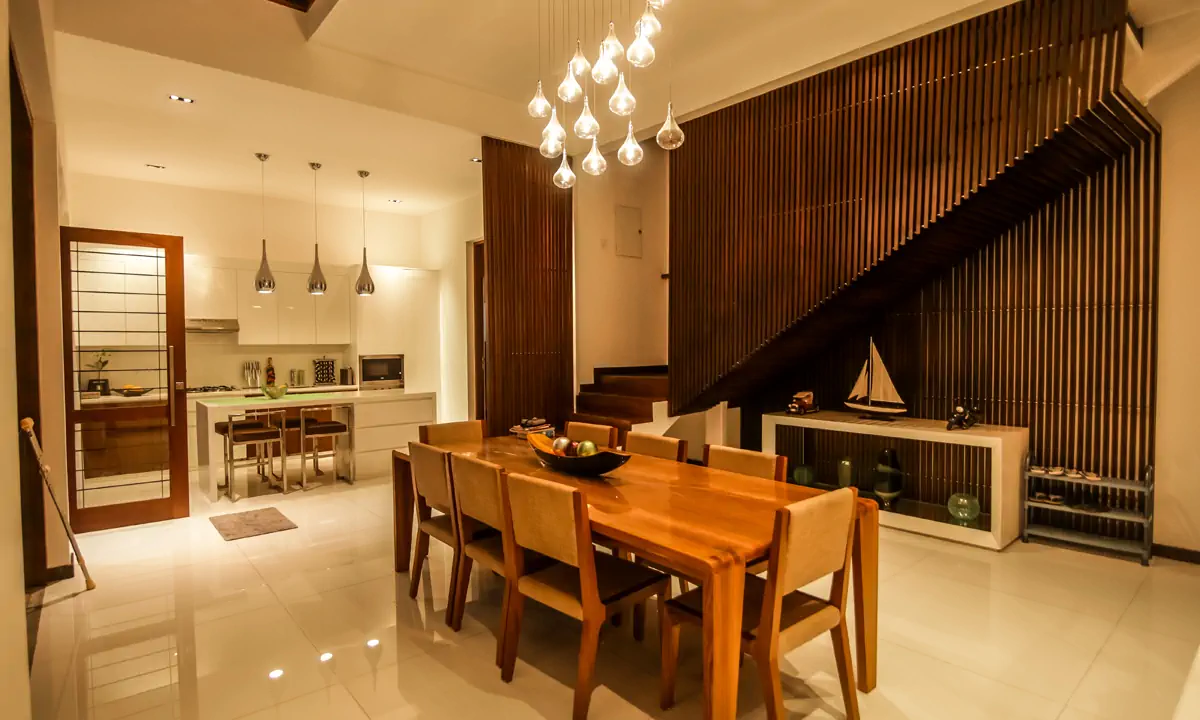Dining area under glass pendants, with the slatted timber stair wall and the kitchen beyond