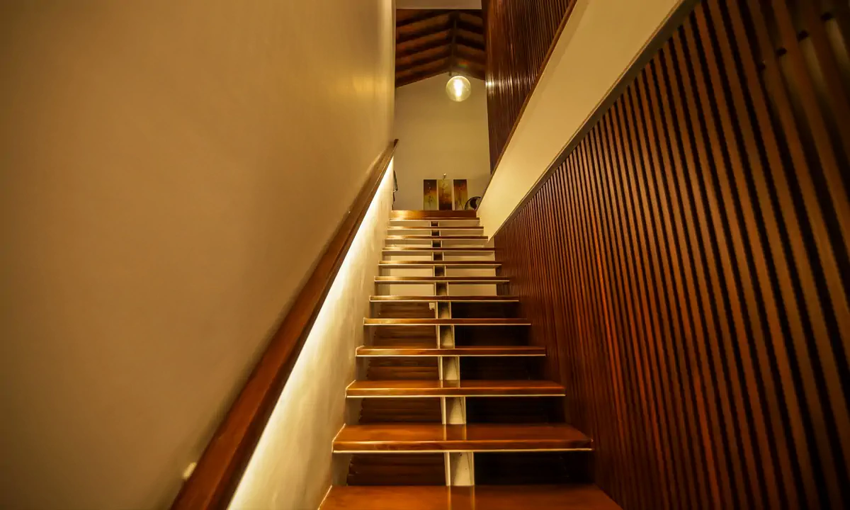 Timber stair lit by a strip light, beside vertical timber slats