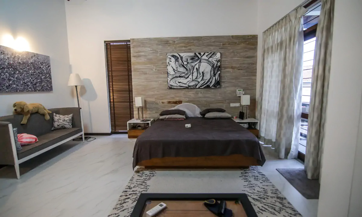Bedroom with a stone-clad wall behind the bed and a black-and-white painting
