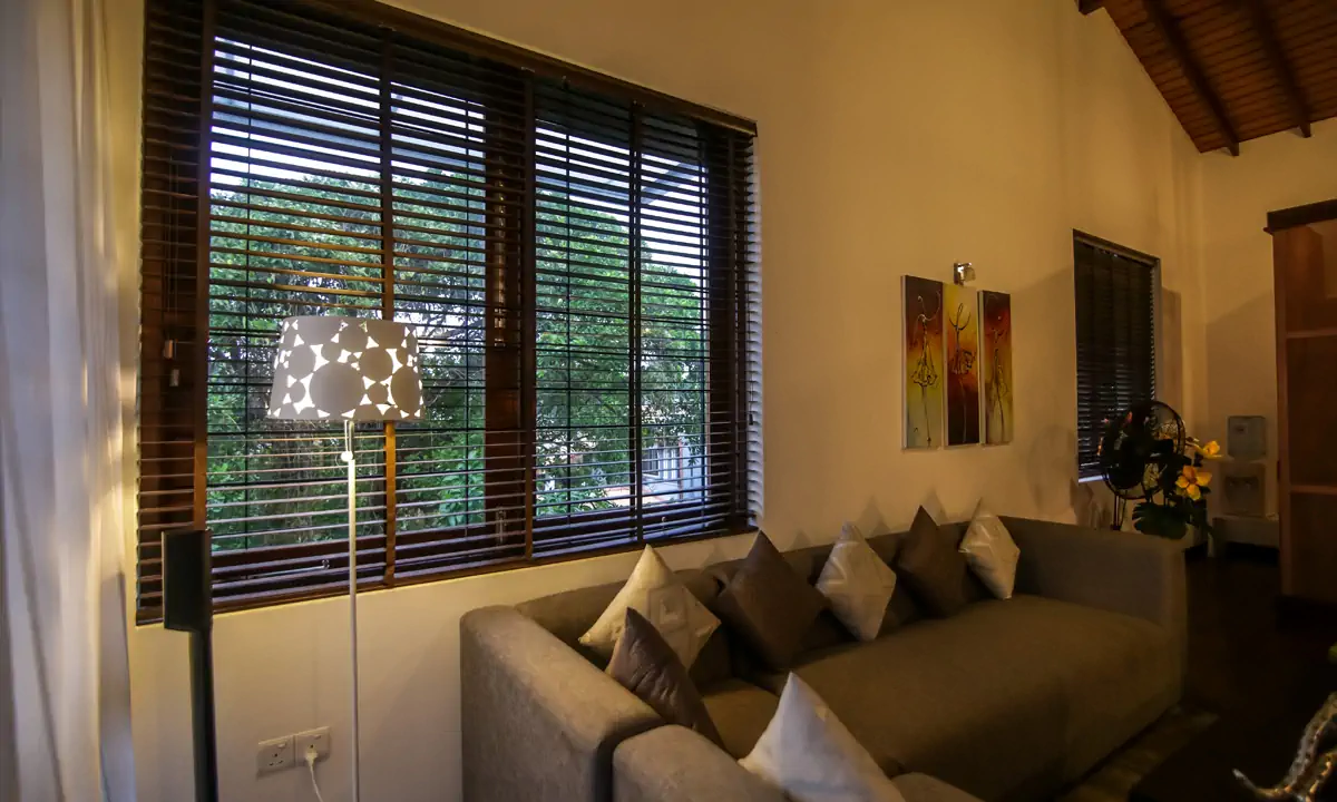 Upstairs sitting room with a grey sofa below a window with timber blinds