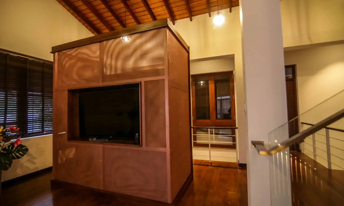 Copper-toned television cabinet under the pitched timber ceiling of the top floor