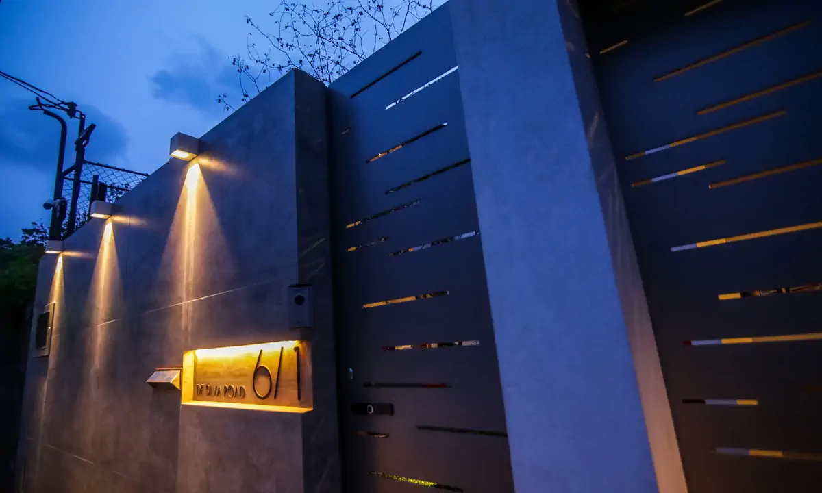Grey gate and wall with slots of light, at dusk