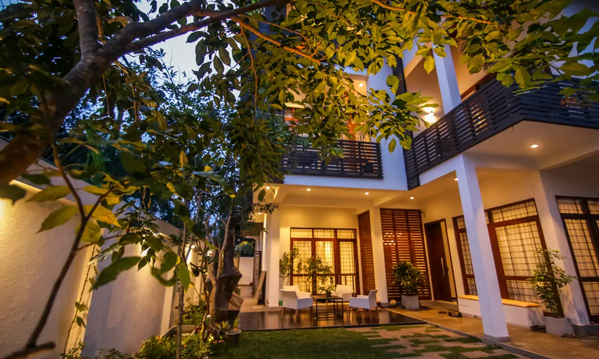 The house at dusk from the garden, with its white verandah and timber-railed balcony