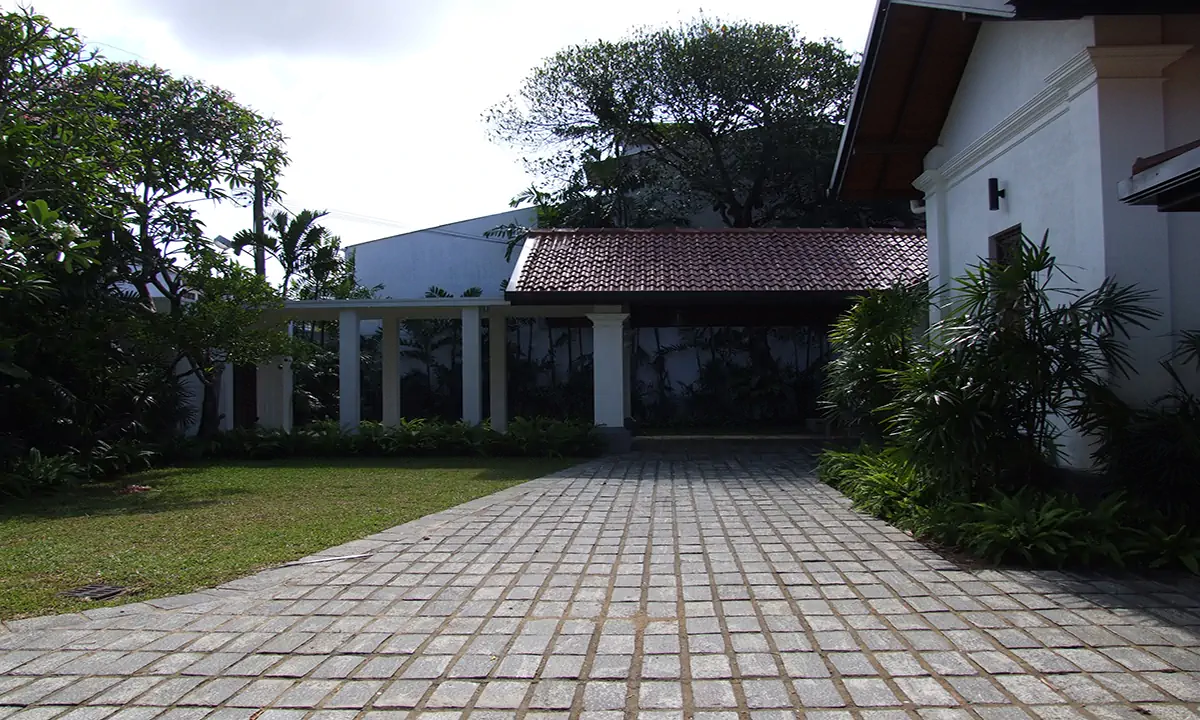 Paved drive across the lawn to a pavilion with a clay-tiled roof