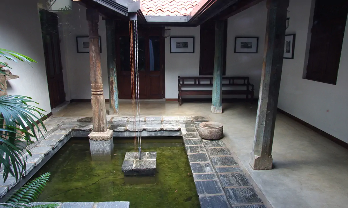 Open courtyard with a shallow pond, weathered timber columns and a rain chain from the tiled roof