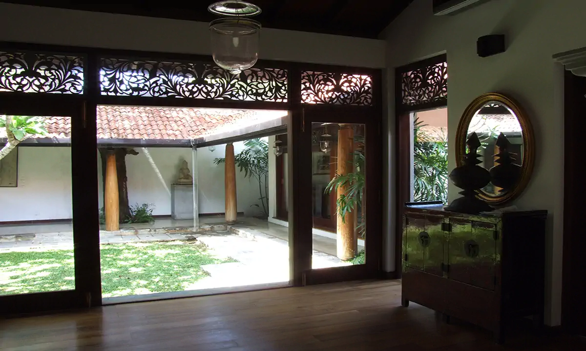 Living room opening to the courtyard through glazed doors under carved timber fretwork