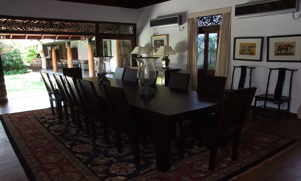 Dining room with a long dark table and a patterned rug, fretwork over the garden doors