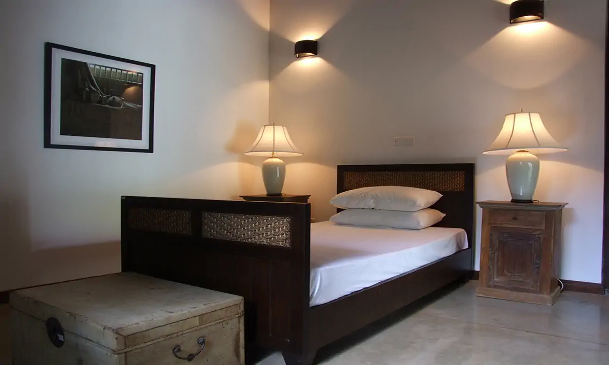 Bedroom with a dark timber bed, table lamps and a framed photograph
