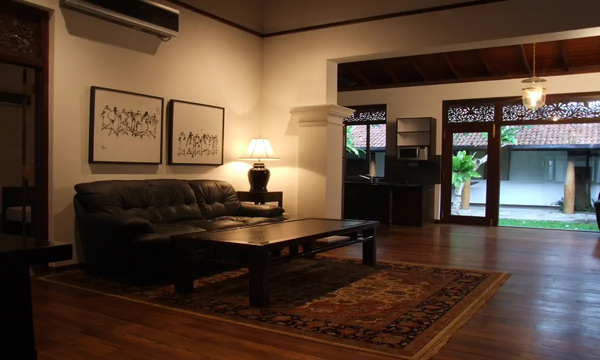 Sitting room with a leather sofa and a patterned rug, opening to the garden