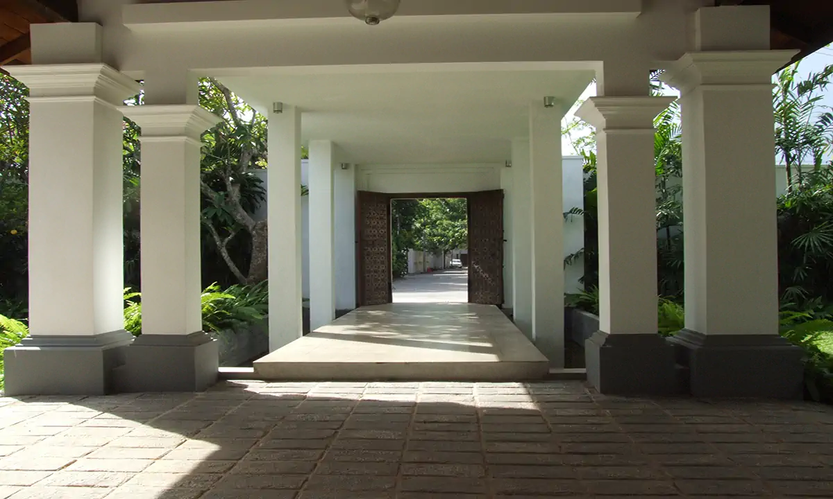 Covered entrance walk between square white columns to the carved front door