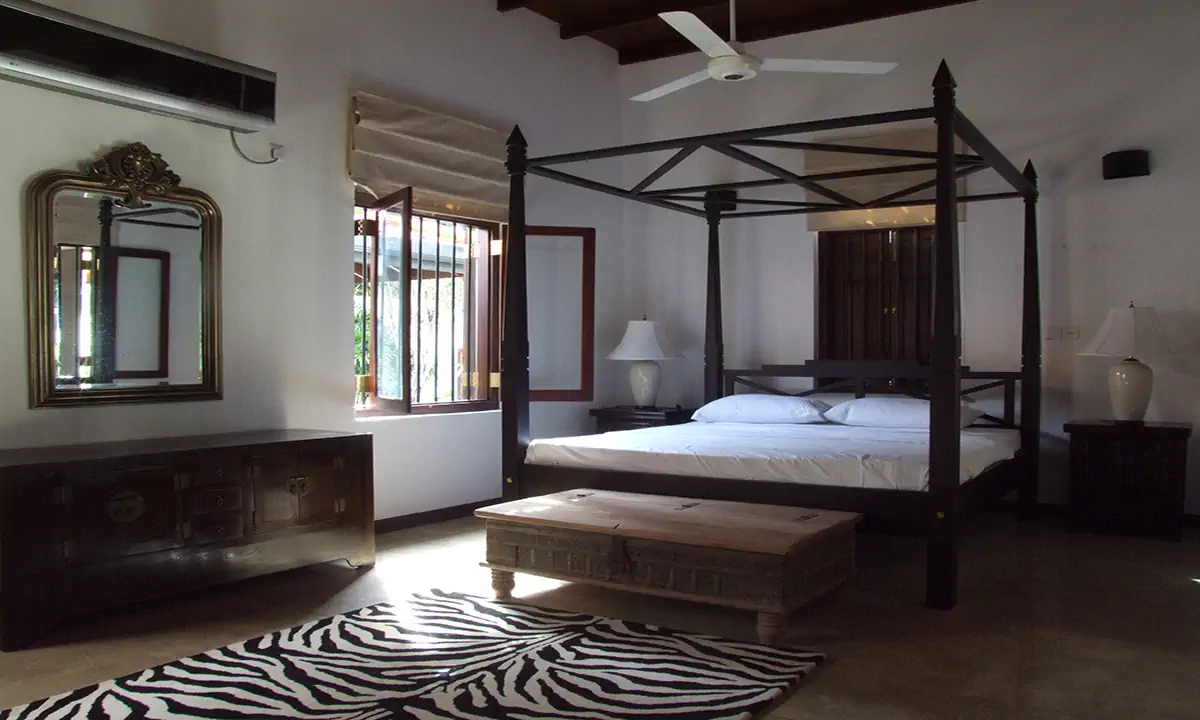 Bedroom with a black four-poster bed and a zebra-print rug