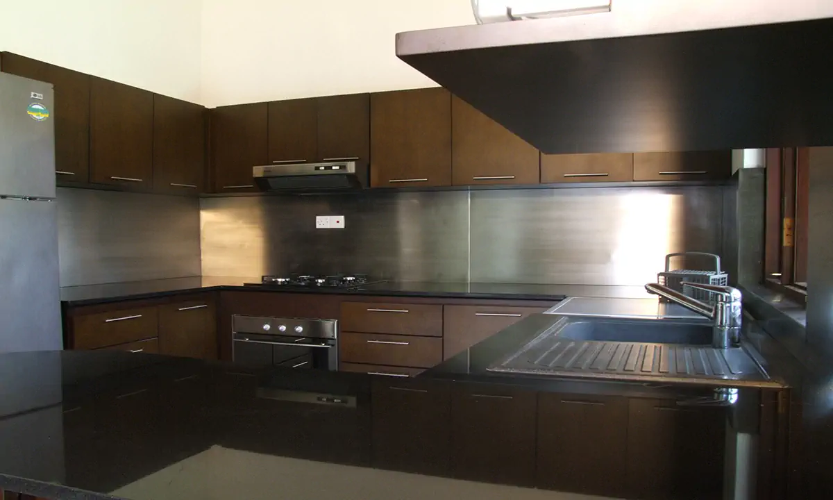 Kitchen with dark timber cabinets, black counters and a steel splashback