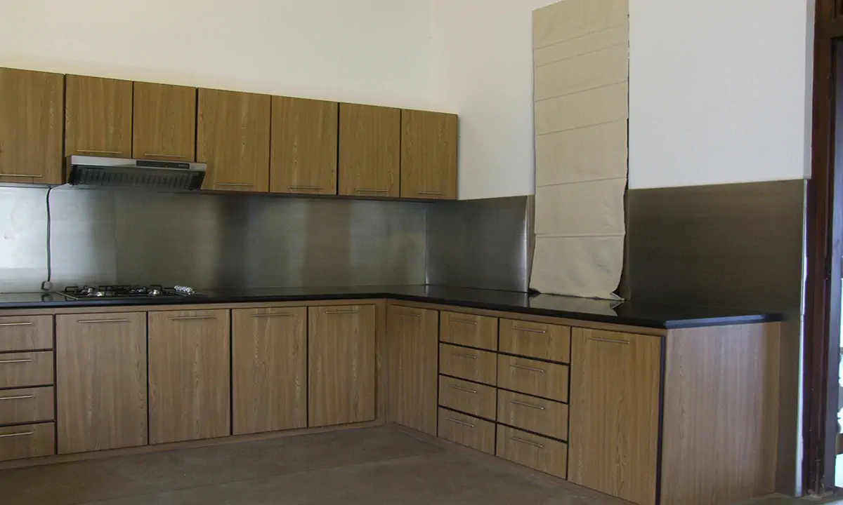 Kitchen with light timber cabinets and a steel splashback