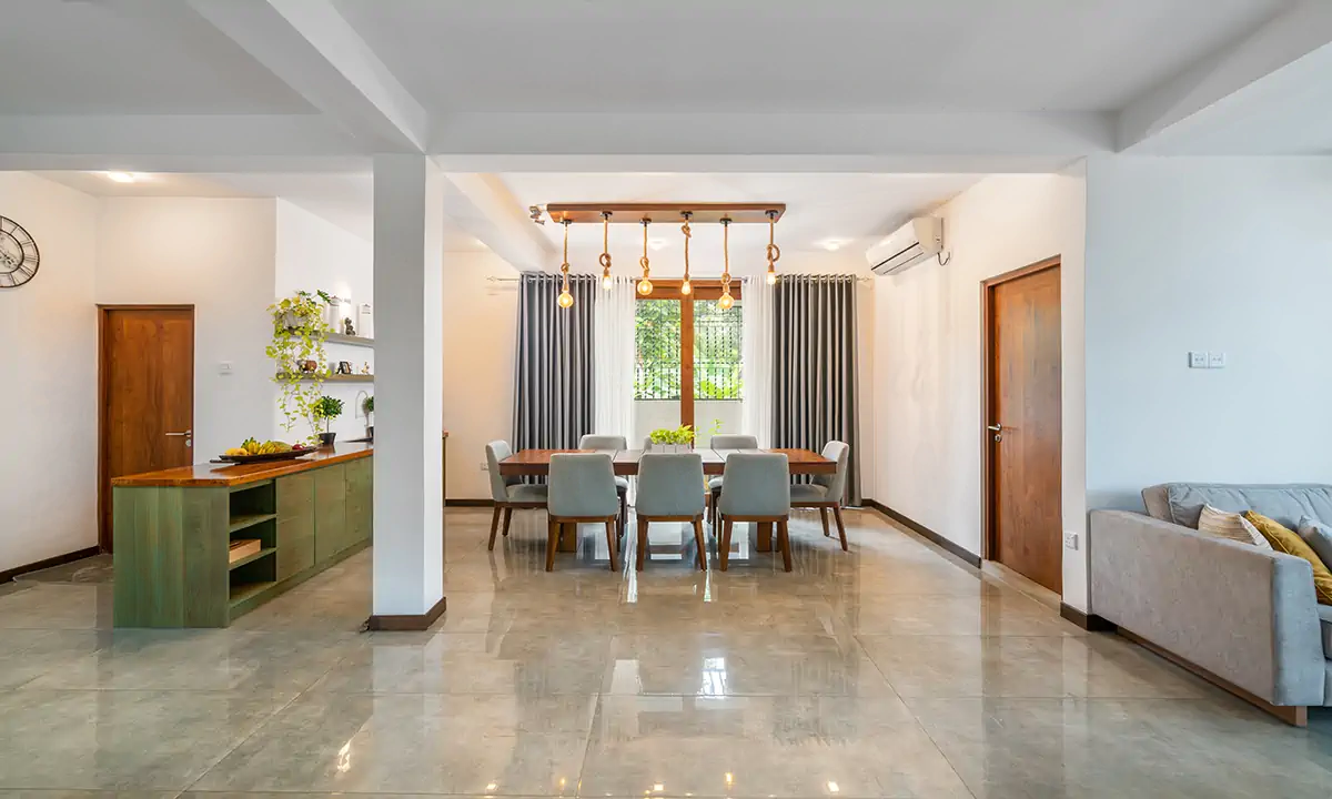 Dining area with pendant lights over a long table, a green sideboard and timber doors