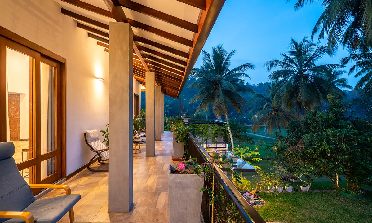First-floor verandah under exposed rafters, looking out over coconut palms
