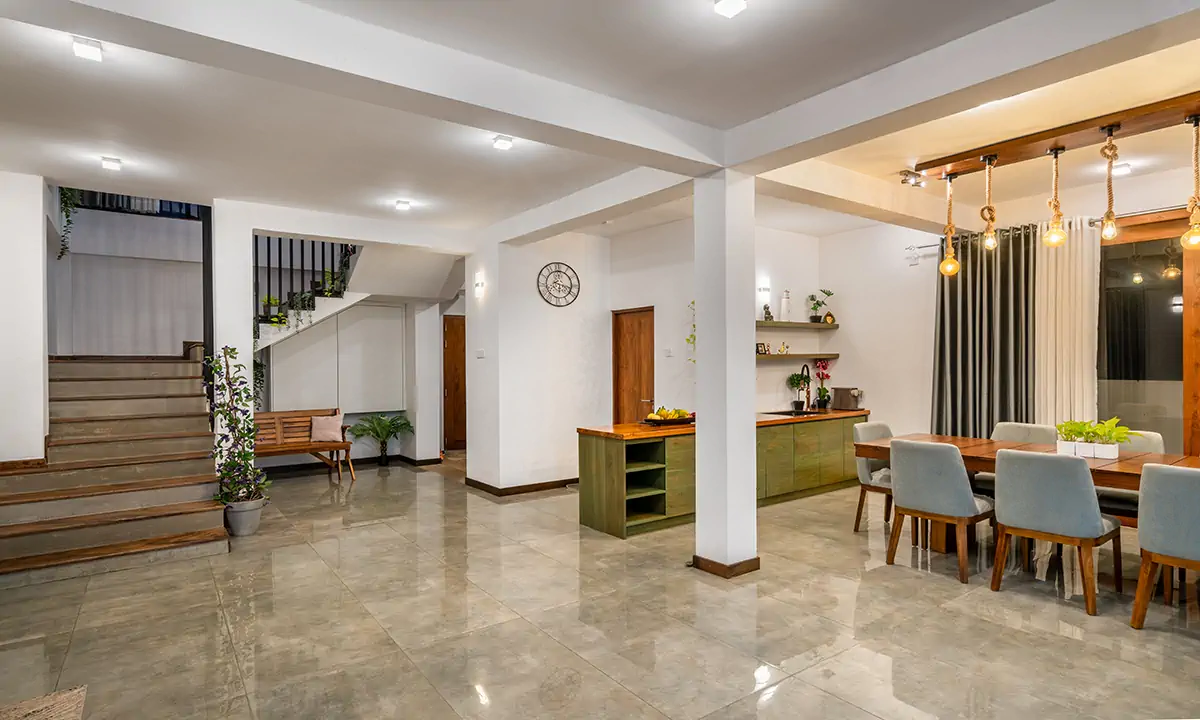 Ground floor with polished floors, the stair and the dining table under pendant lights