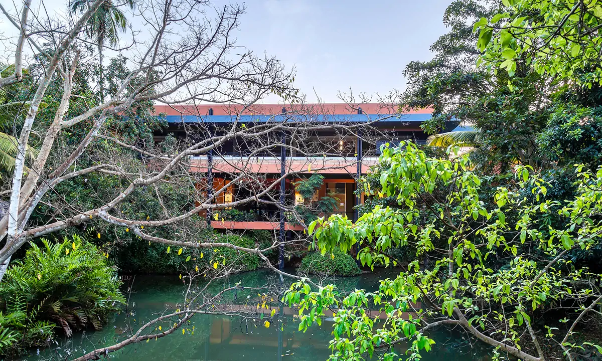 Thurulie seen through the trees across the water, its long low roofs above the planting