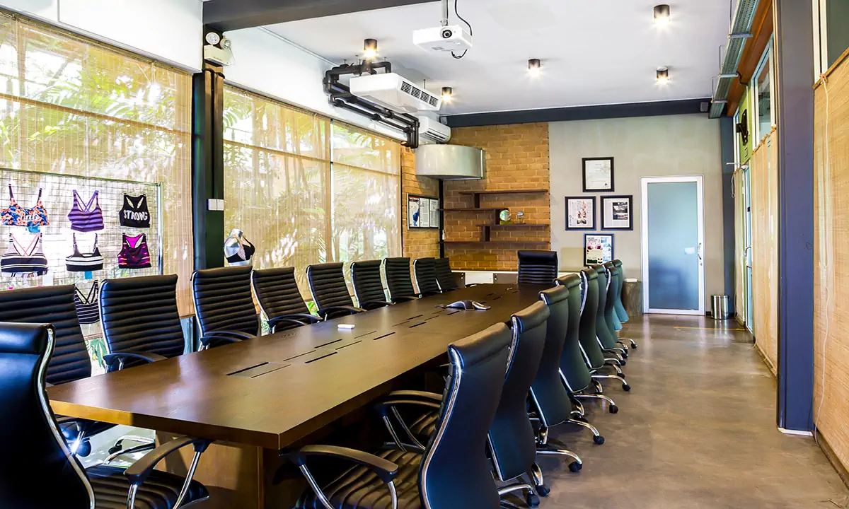 Boardroom with a long timber table and black leather chairs