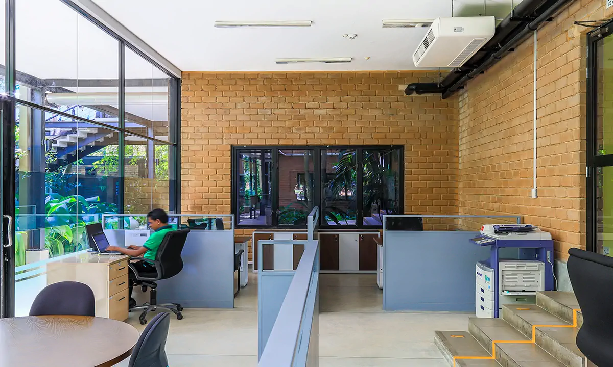 Office with open desks and glass partitions inside eco-brick walls