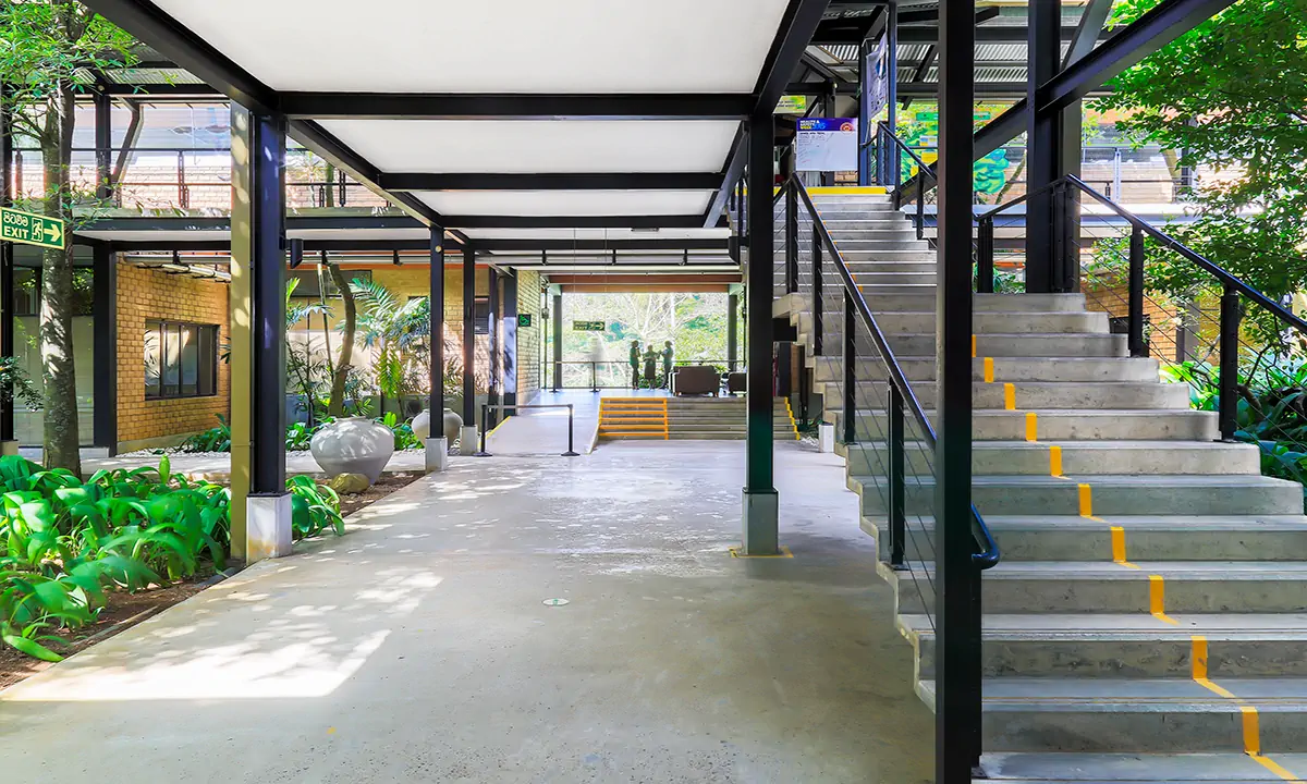 Open ground floor with a concrete stair beside a planted courtyard