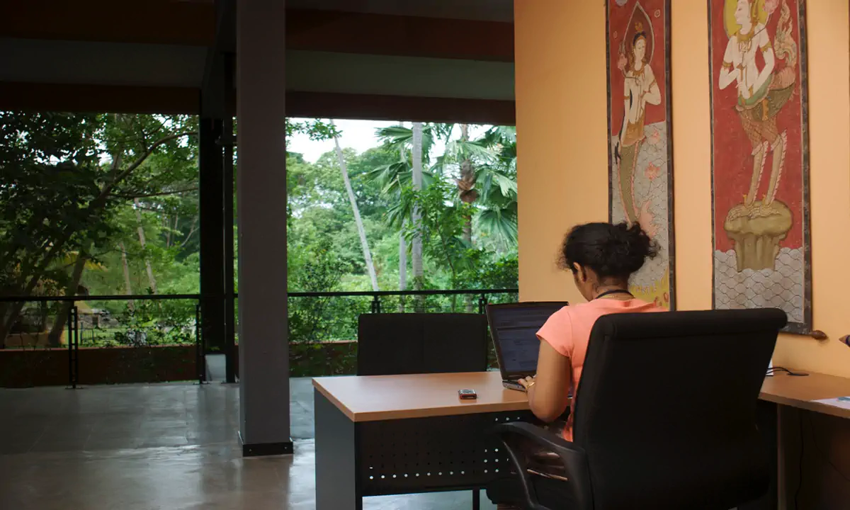 Workspace open to the trees, with traditional painted figures on the wall