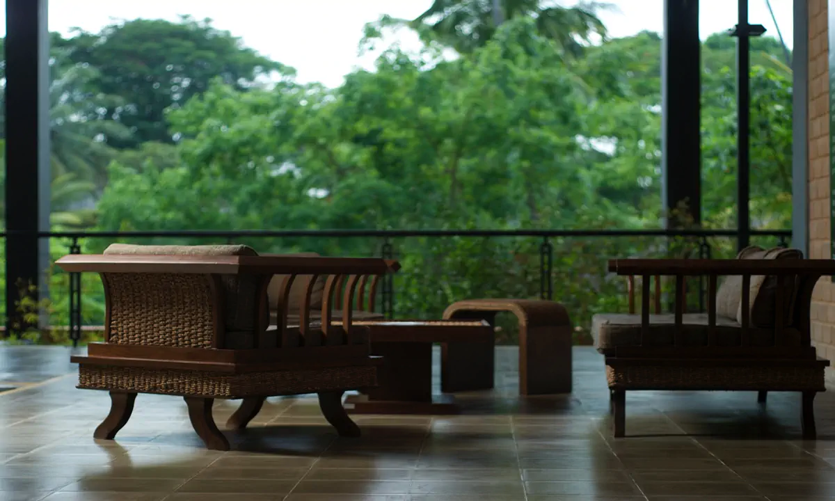 Timber and cane lounge chairs on a covered terrace above the trees