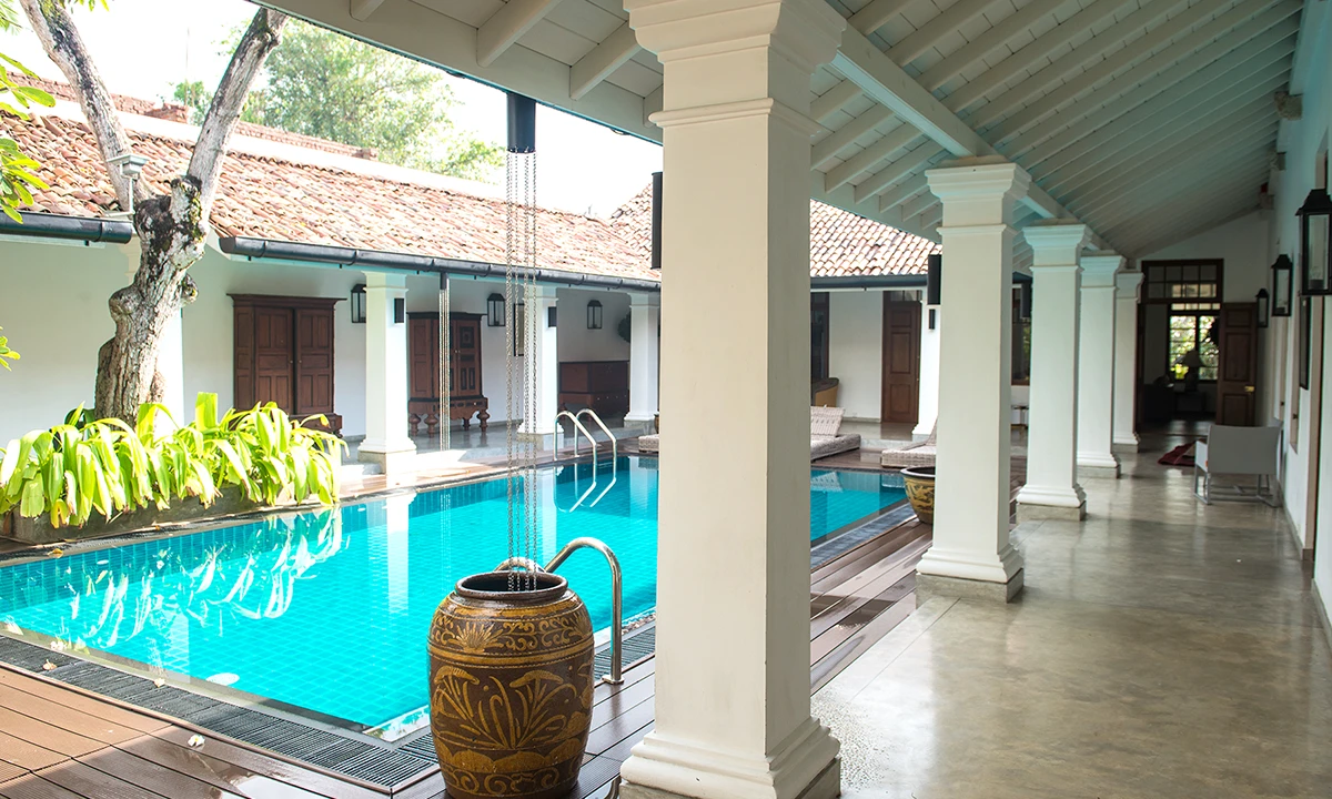 Pool courtyard seen from the verandah, with white columns and a large glazed urn