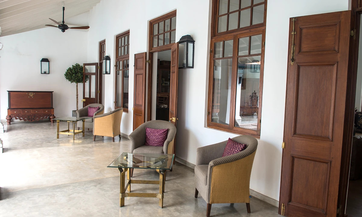 Sitting area with armchairs and a glass table beside tall timber doors
