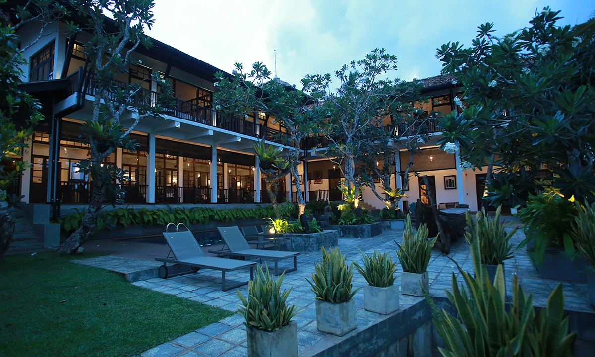 The villa at dusk from the garden, sun loungers in front of the two-storey wing
