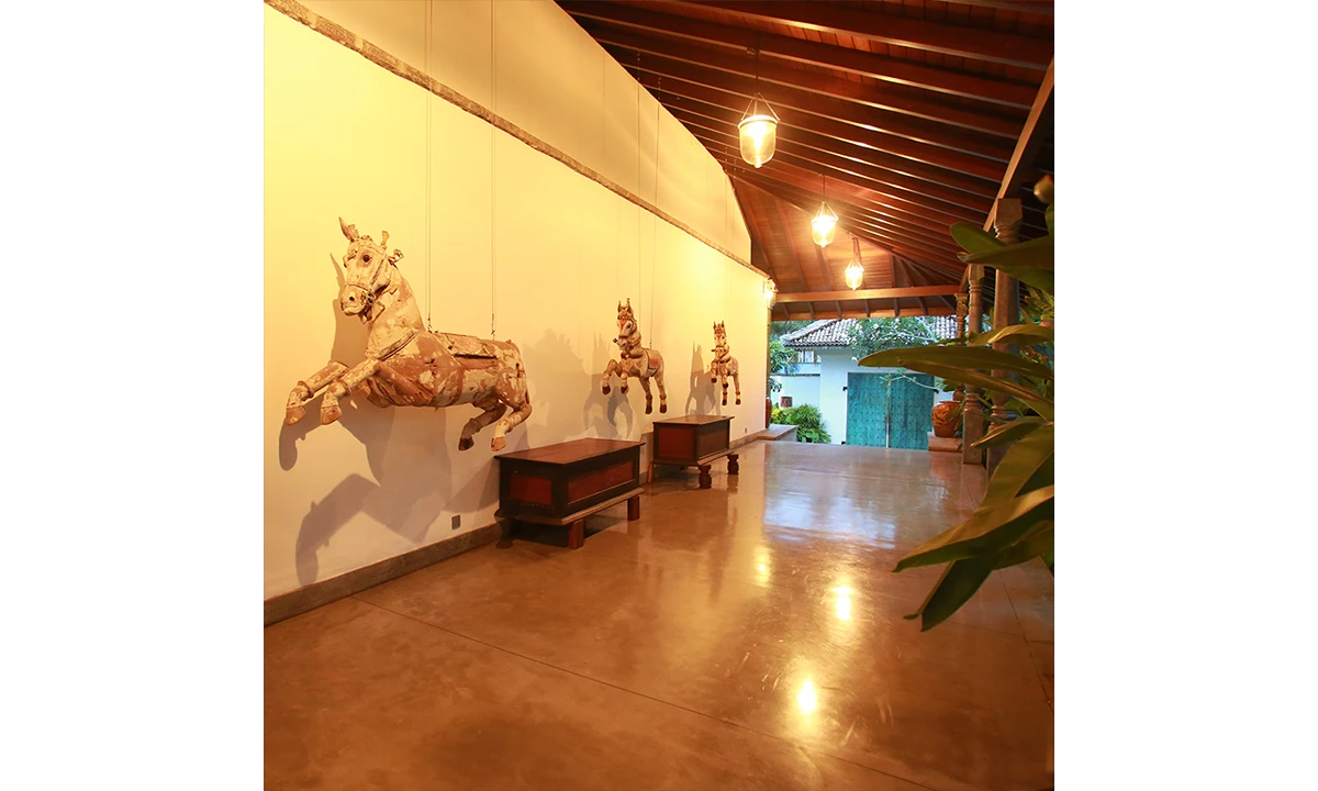 Hallway under a timber roof, with carved timber horses along the wall