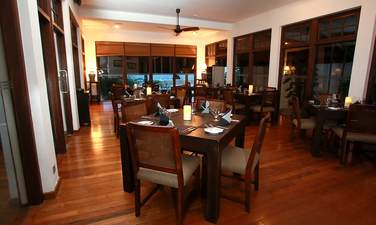 Dining room with dark timber tables laid for dinner and glazed timber screens