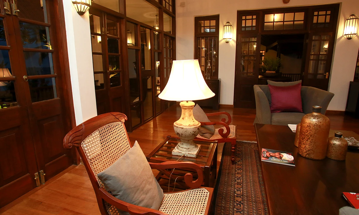 Sitting room with a cane-backed armchair, a table lamp and timber-framed doors