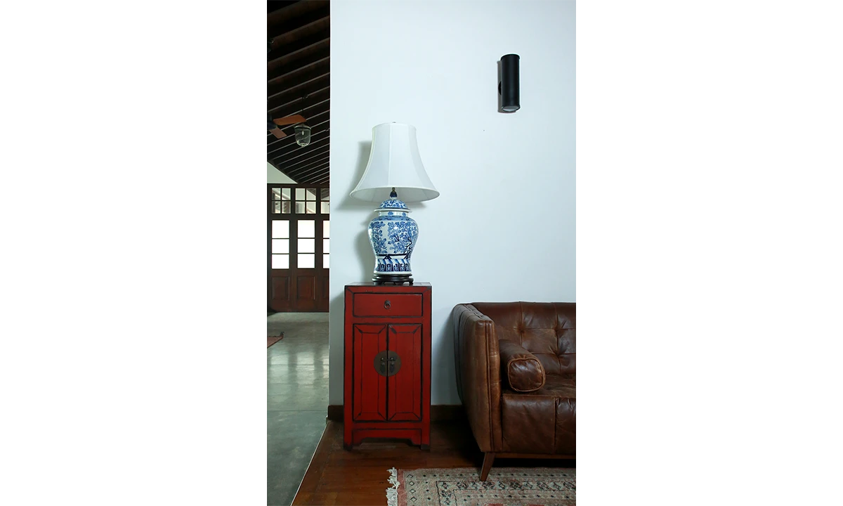 Red lacquered cabinet and a blue-and-white lamp beside a leather armchair